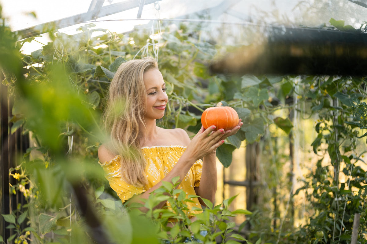 Elsa met een pompoen in haar kas vol groen