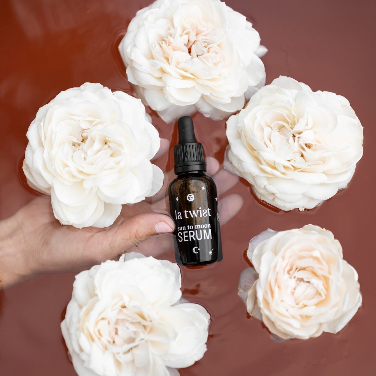 Sun to Moon Serum tussen witte rozen in een bad