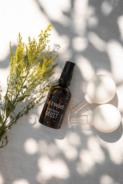 Wild Flora Mist met glazen cupping cups en gele bloemen in het zonlicht