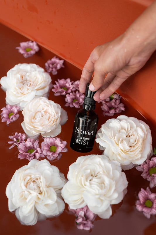 Wild Flora Mist among white roses and pink flowers in a bath